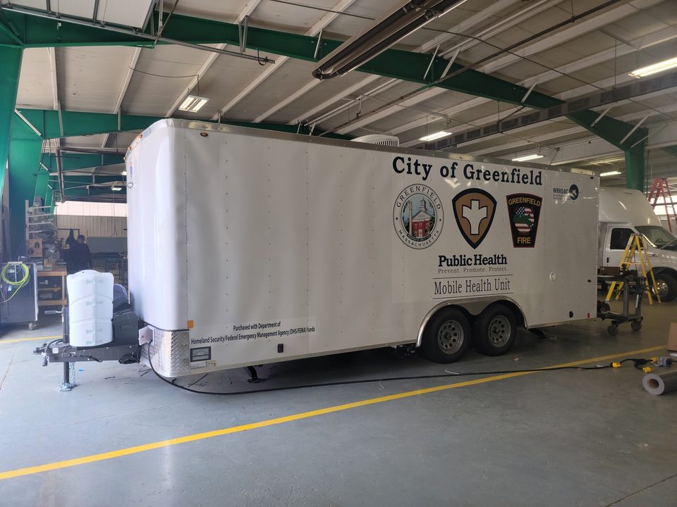 Greenfield mobile health trailer, side, in the plant